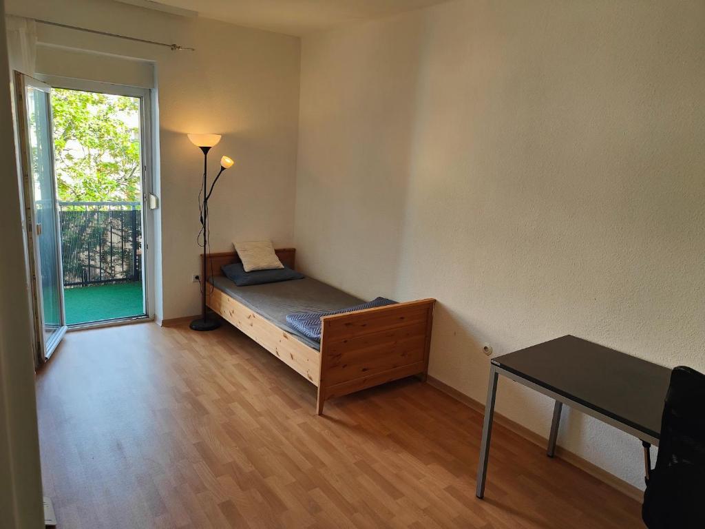 um quarto com uma cama, uma mesa e uma janela em 3 min walk to Bahnhof -Peaceful room with Balcony em Mannheim