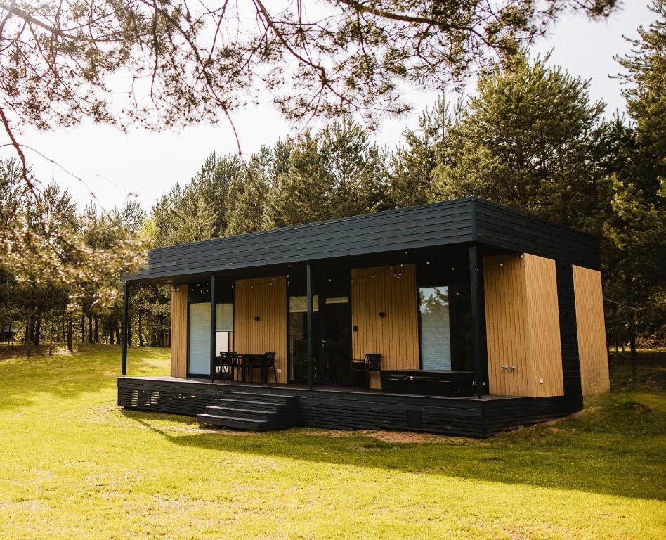 een klein zwart en bruin gebouw in een veld bij Chill Hill Kalviai 