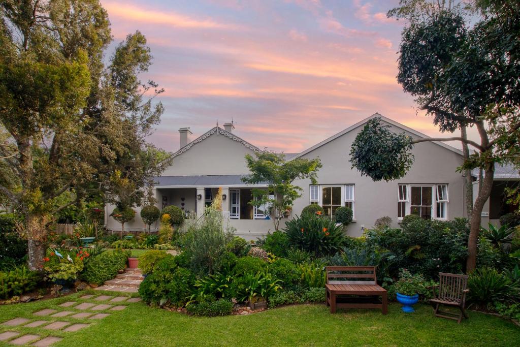a white house with a garden at sunset at Fiddlewood Fields Guest House in Grahamstown