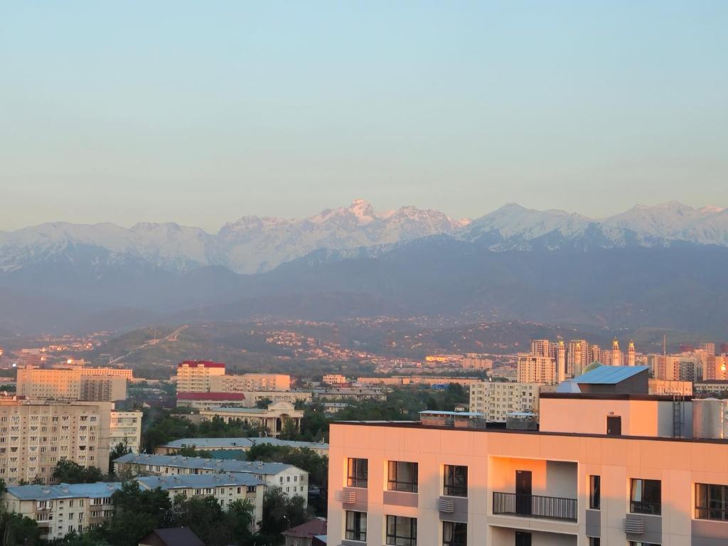 a view of a city with mountains in the background at Alpine serenity deLuxe apartment with MOUNTAIN views near the ADK shopping center and Sairan METRO station in Almaty