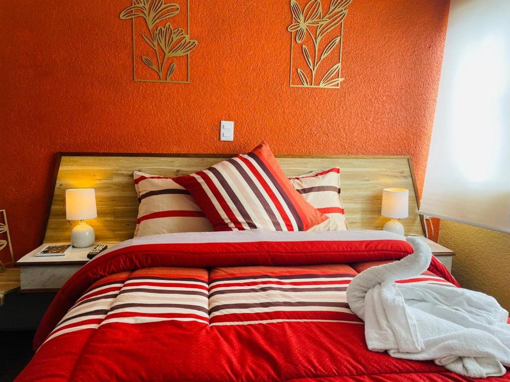 een slaapkamer met een bed met een oranje muur bij Hotel Los Diamantes Orizaba in Orizaba