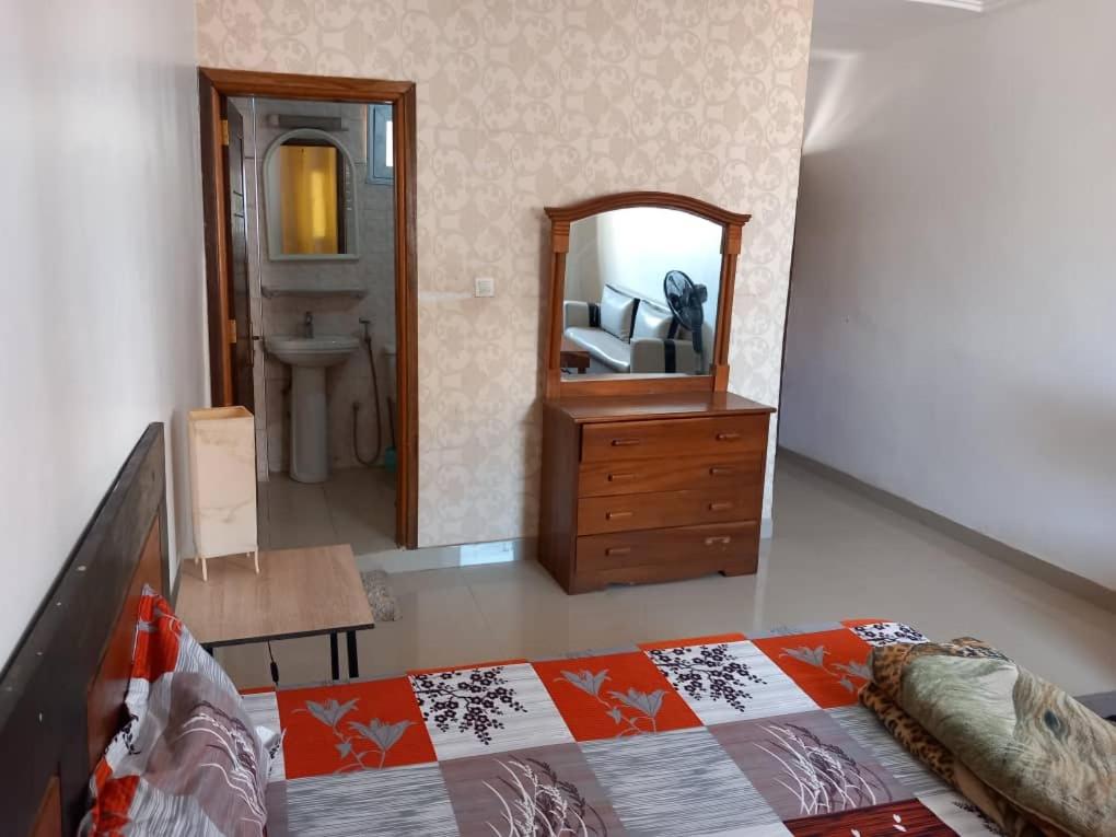 1 dormitorio con cama, tocador y espejo en fleur, en Dakar
