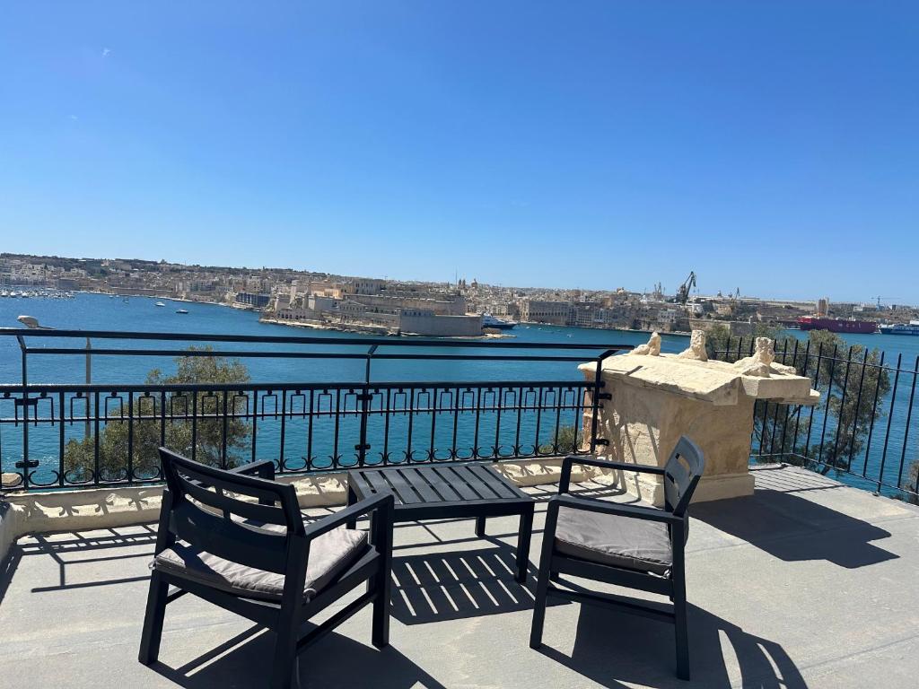 een tafel en stoelen op een balkon met uitzicht op het water bij 79 Sam's Place, Valletta in Valletta