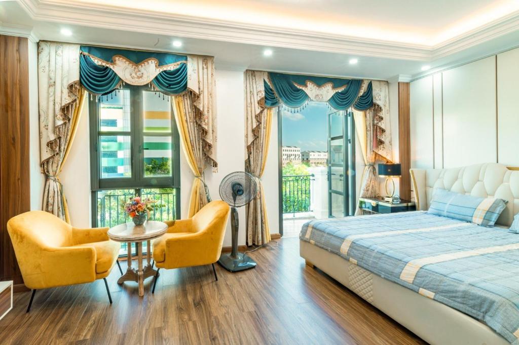 een slaapkamer met een bed en 2 stoelen en een balkon bij Villa Homestay Ocean Park 1 Gia Lâm in Hanoi