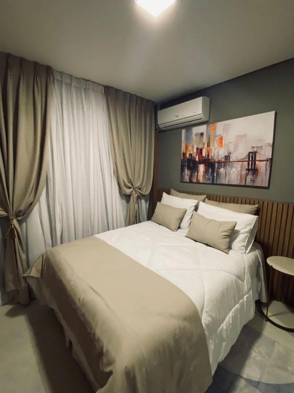 een slaapkamer met een groot bed met witte lakens bij Studios London in Resende