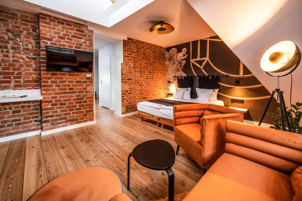 a room with a brick wall and a bed and a couch at Apartamenty Schoeps Residence in Poznań