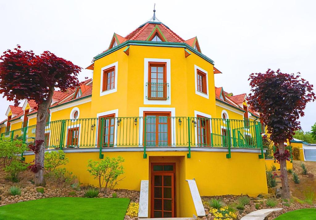 Una casa amarilla con balcón en la parte superior. en Hotel Römerstein - Die Wohlfühloase, en Loipersdorf bei Fürstenfeld