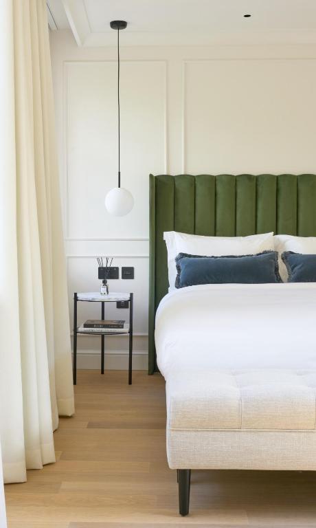 a bedroom with a bed with a green headboard and a table at The Store in Oxford