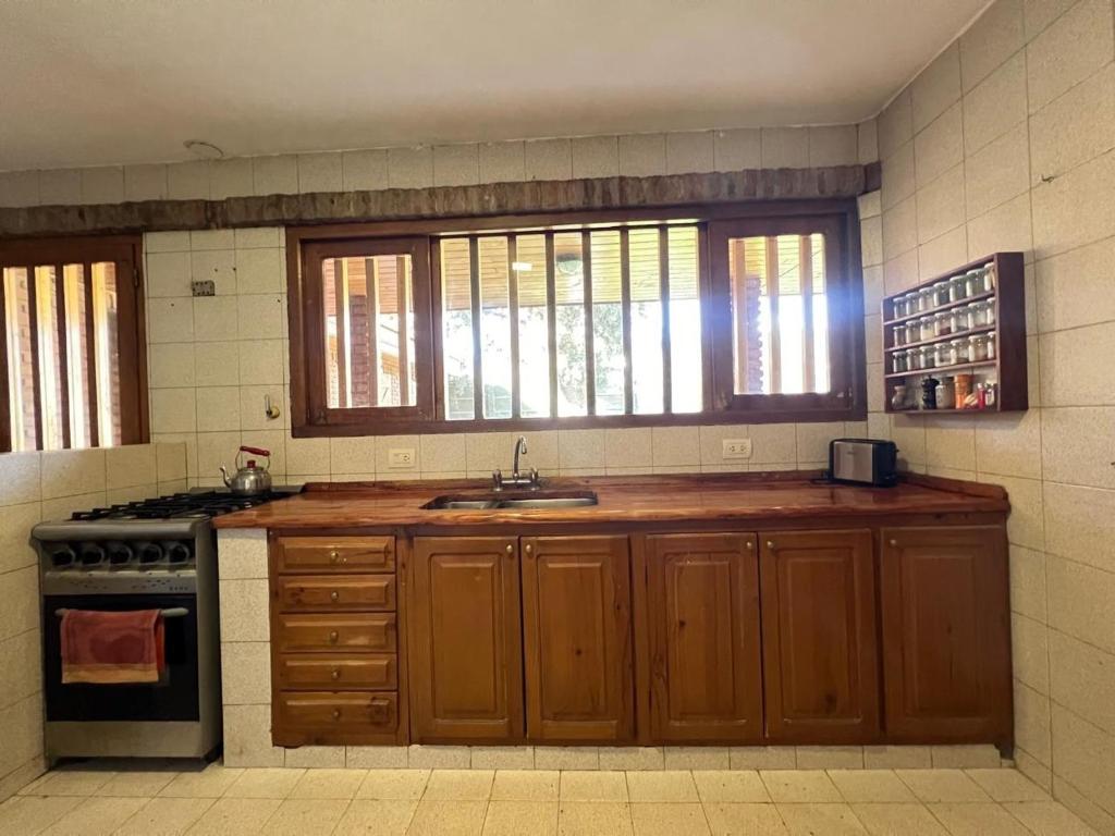 a kitchen with wooden cabinets and a sink and a stove at Habitación en chalet, Cipolletti in Cipolletti