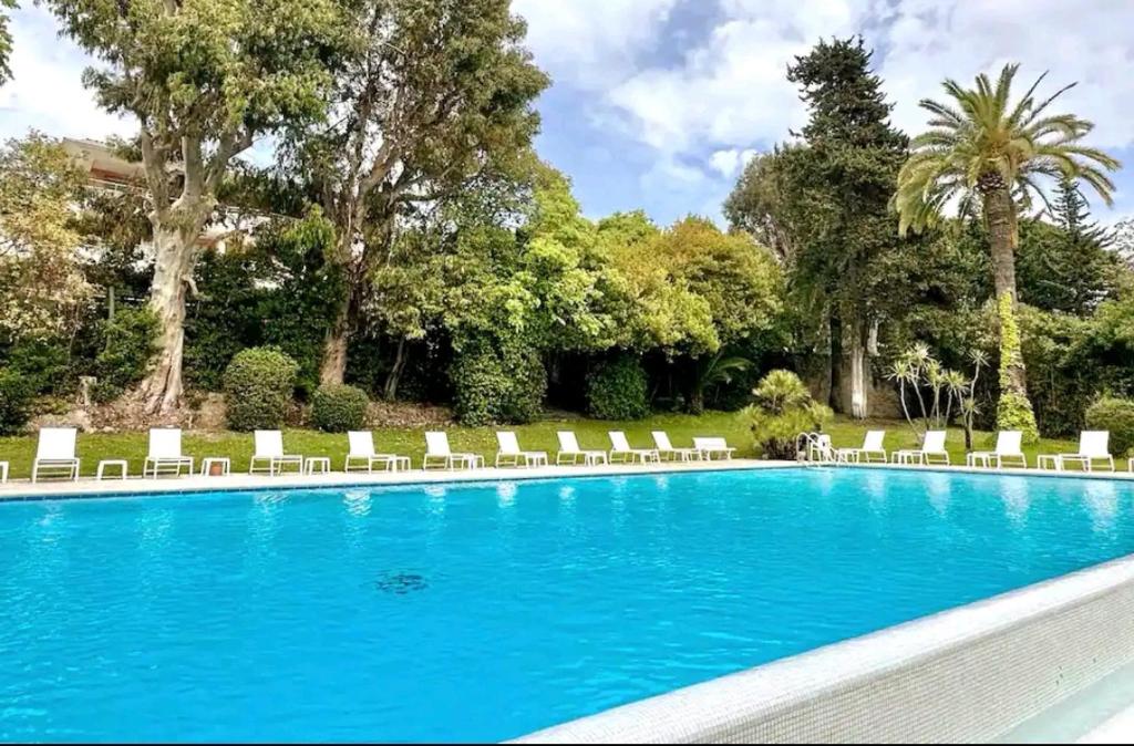 une grande piscine avec des chaises longues et des arbres dans l'établissement Magnifique et grand studio, piscine, parking, très calme résidence de standing, à Cannes