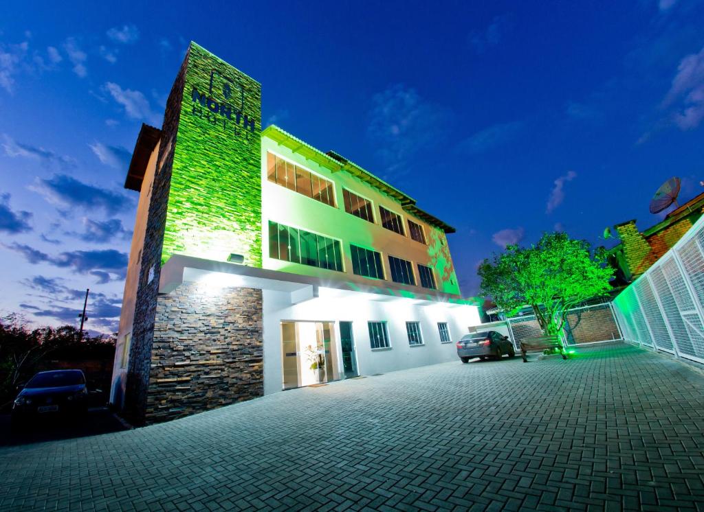 um edifício com uma fachada verde à noite em North Hotel - Aeroporto em Chapecó