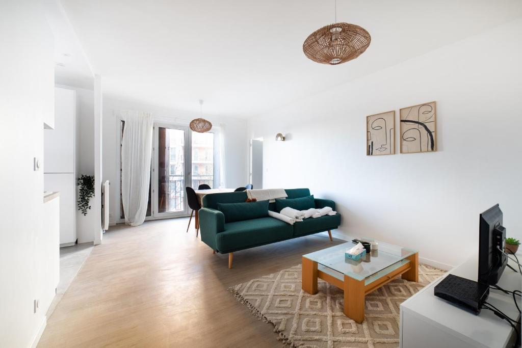 uma sala de estar com um sofá verde e uma mesa em Appartement rénové Proche Paris - 5 min transport em Montrouge