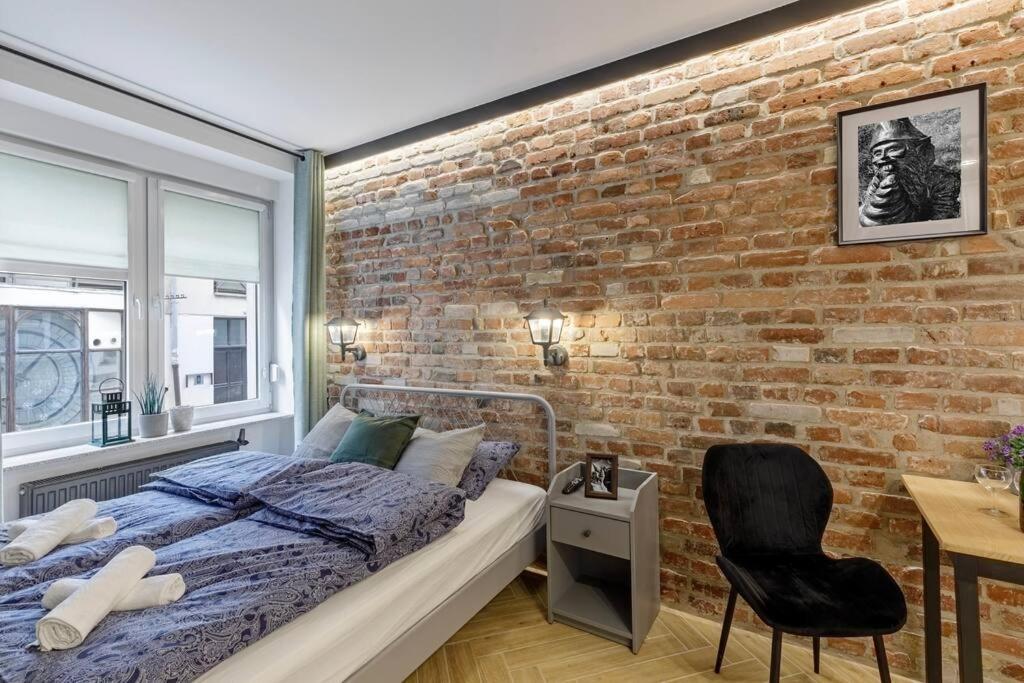 1 dormitorio con pared de ladrillo, cama y silla en Weronika's Urban Hideaway, en Wroclaw