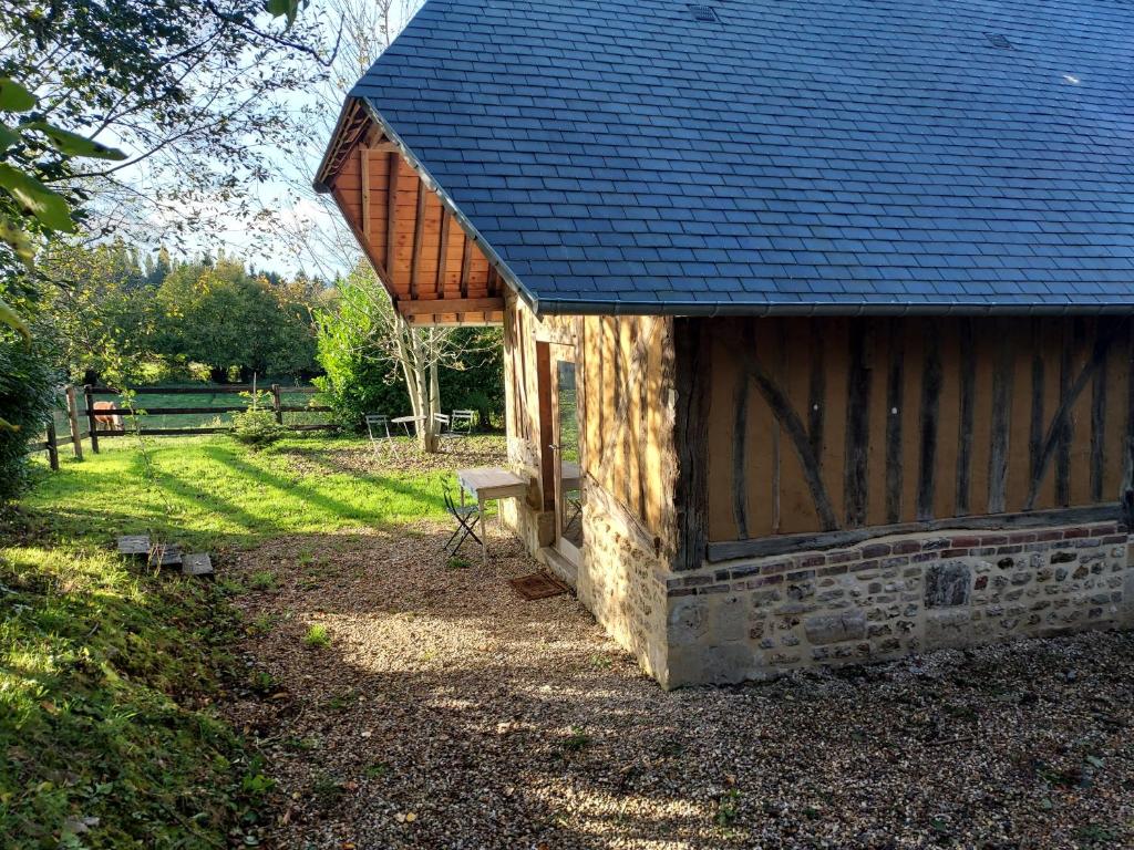 un bâtiment avec un toit bleu avec un banc à l'extérieur dans l'établissement Le Cocon, Gîte du Manoir de La Porte, à Les Authieux-sur-Calonne