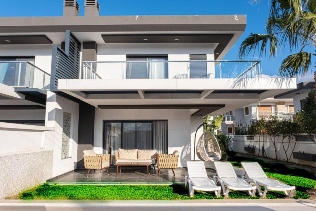 ein Haus mit einer Terrasse mit Stühlen und einem Balkon in der Unterkunft Çeşme lüks huzurlu yeni villa in Cesme