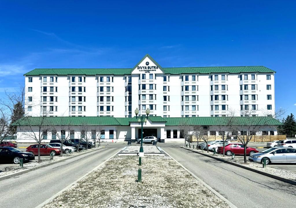a large white building with a green roof on a street at Divya Sutra Plaza and Conference Centre Calgary Airport in Calgary
