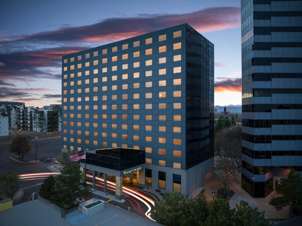 un edificio de oficinas alto con una puesta de sol en el fondo en Hyatt Place Denver Cherry Creek en Denver