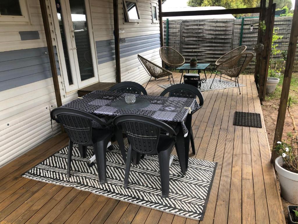 - une table et des chaises noires sur une terrasse couverte dans l'établissement Mobilhome à Fréjus à 15 minute de la mer sur terrain indépendant, à Fréjus