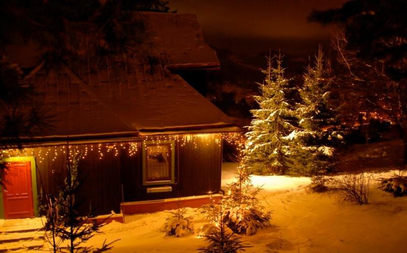 ヴィスワにあるRezydencja Święty Spokójの雪の中の灯りとクリスマスの木がある家