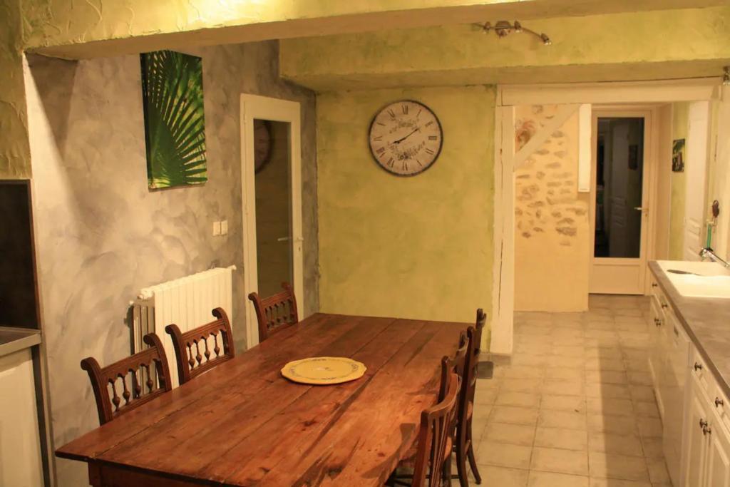 una mesa de madera en una cocina con reloj en la pared en Gîte Le Laurentin, en Saint-Laurent-du-Plan