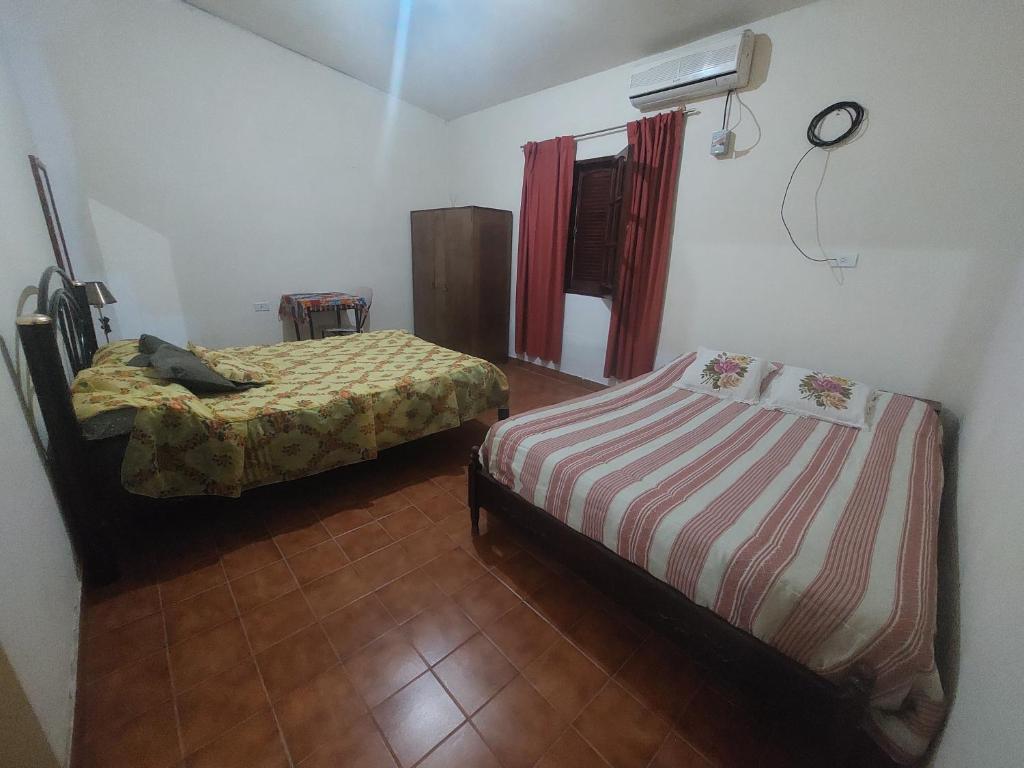 um quarto com 2 camas e uma janela com uma ventoinha em Hospedaje La Gringa em Tinogasta