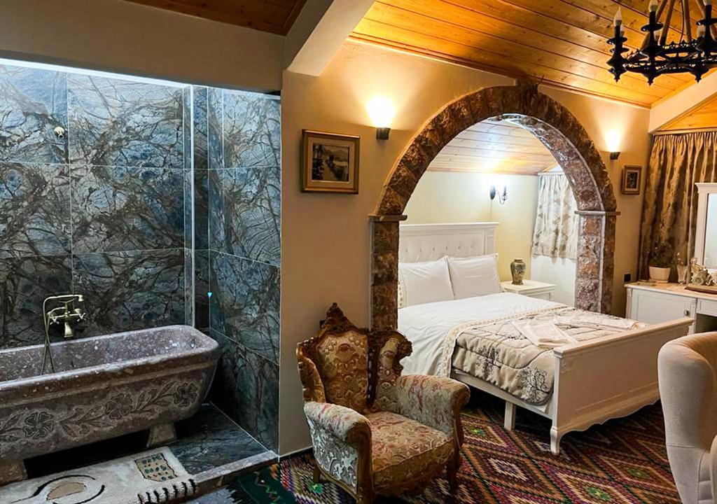 a bedroom with a tub and a bed and a sink at Villa Parku Rinia in Korçë