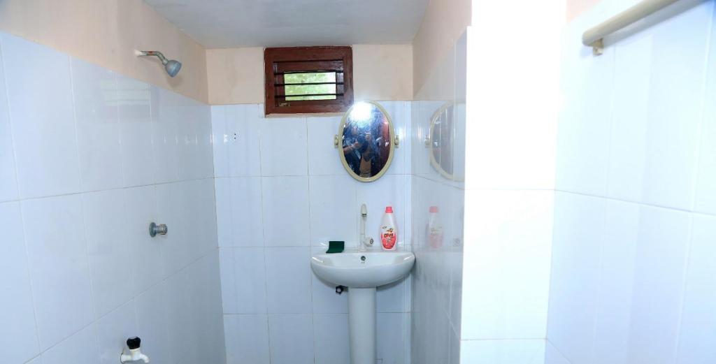 a white bathroom with a sink and a shower at Urumpirai Holidays in Jaffna