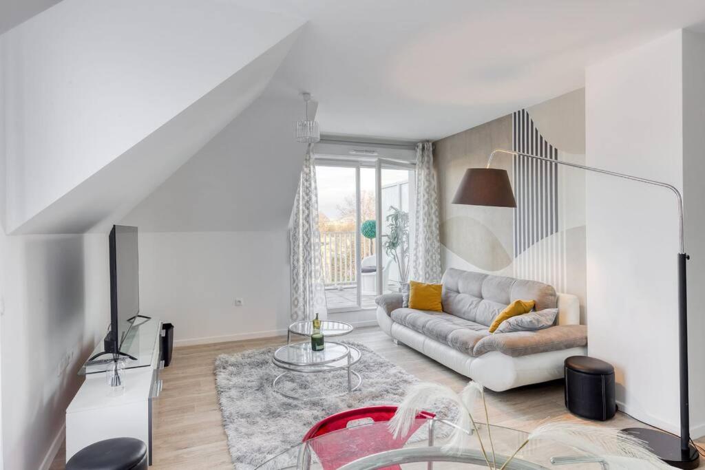 uma sala de estar com um sofá e uma mesa em Appartement Neuf avec Terrasse em Bobigny