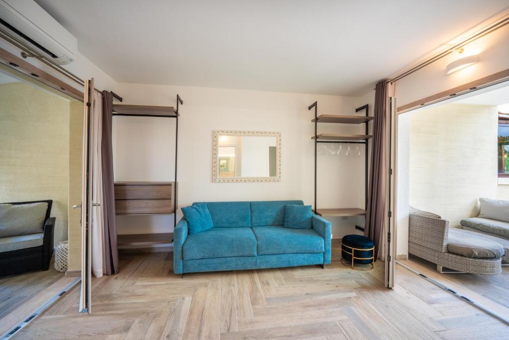 a living room with a blue couch and a bed at Suimi's Hotel in Villasimius