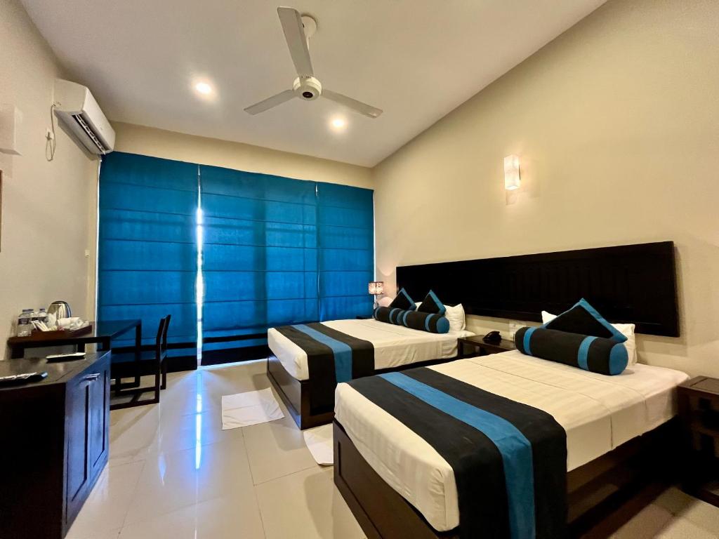 a hotel room with two beds and a television at Hotel Randiya Anuradhapura in Anuradhapura