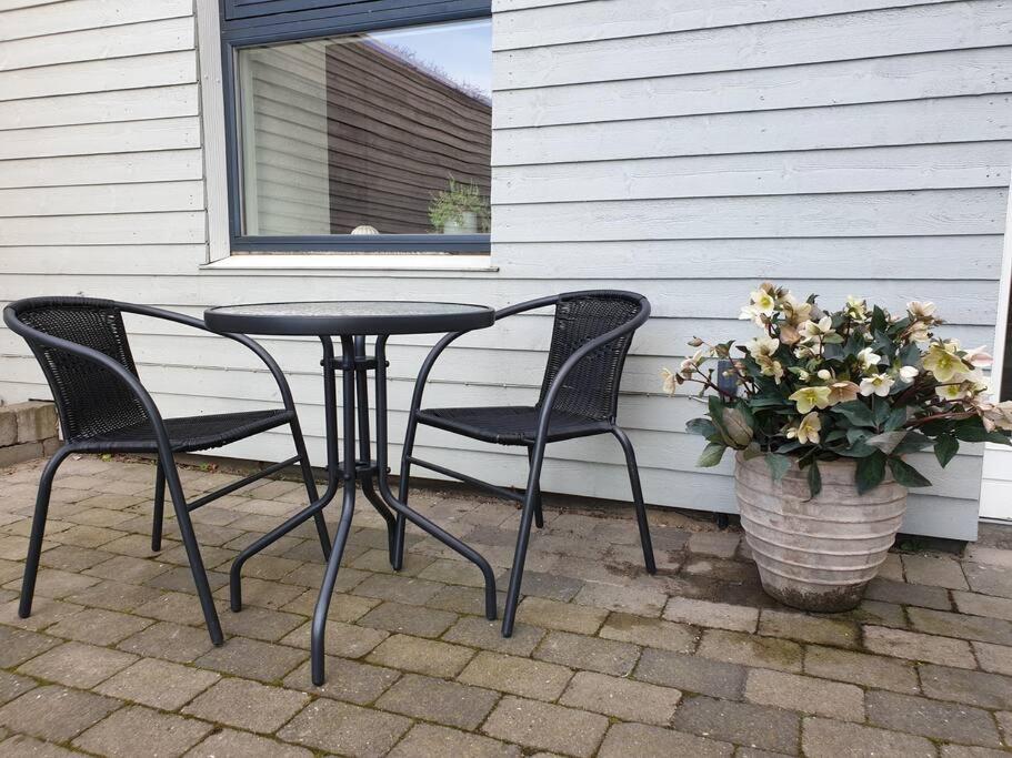 a patio table and two chairs and a pot of flowers at Charmerende villalejlighed på 80 kvm inklusiv gårdhave in Viby