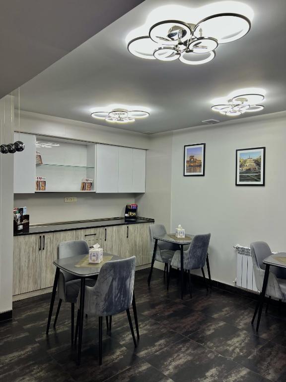 a dining room with tables and chairs and a kitchen at Mashtots Hotel in Yerevan