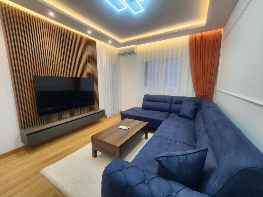 een woonkamer met een blauwe bank en een televisie bij Eleven Apartment in Podgorica