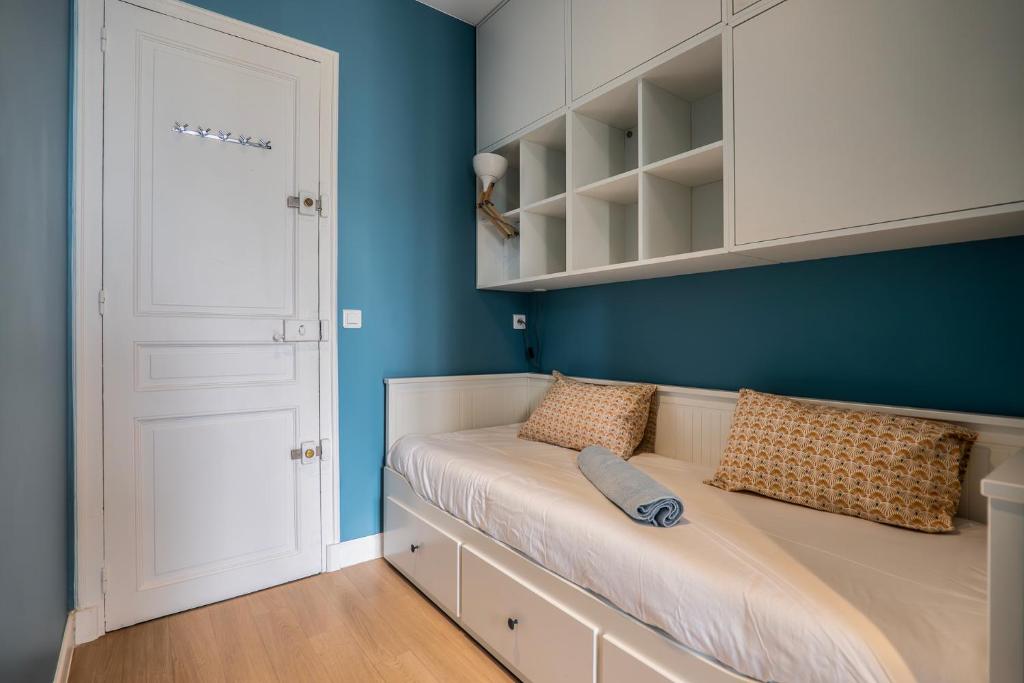 une chambre avec un lit aux murs bleus et une porte blanche dans l'établissement GoodGuest-Trocadéro Tour Eiffel Bail Mobilité, à Paris