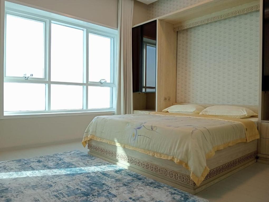 a bedroom with a large bed with two windows at Corniche Tower in Ajman 
