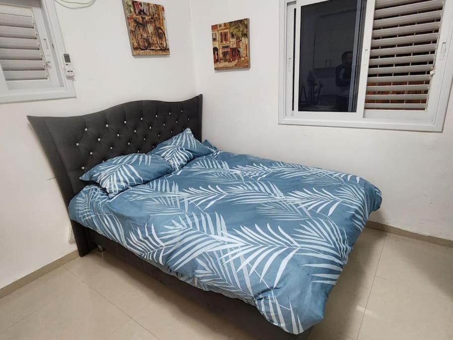 Una cama con edredón azul y almohadas en un dormitorio en Luxury Huge Suite Near the beach, en Bat Yam