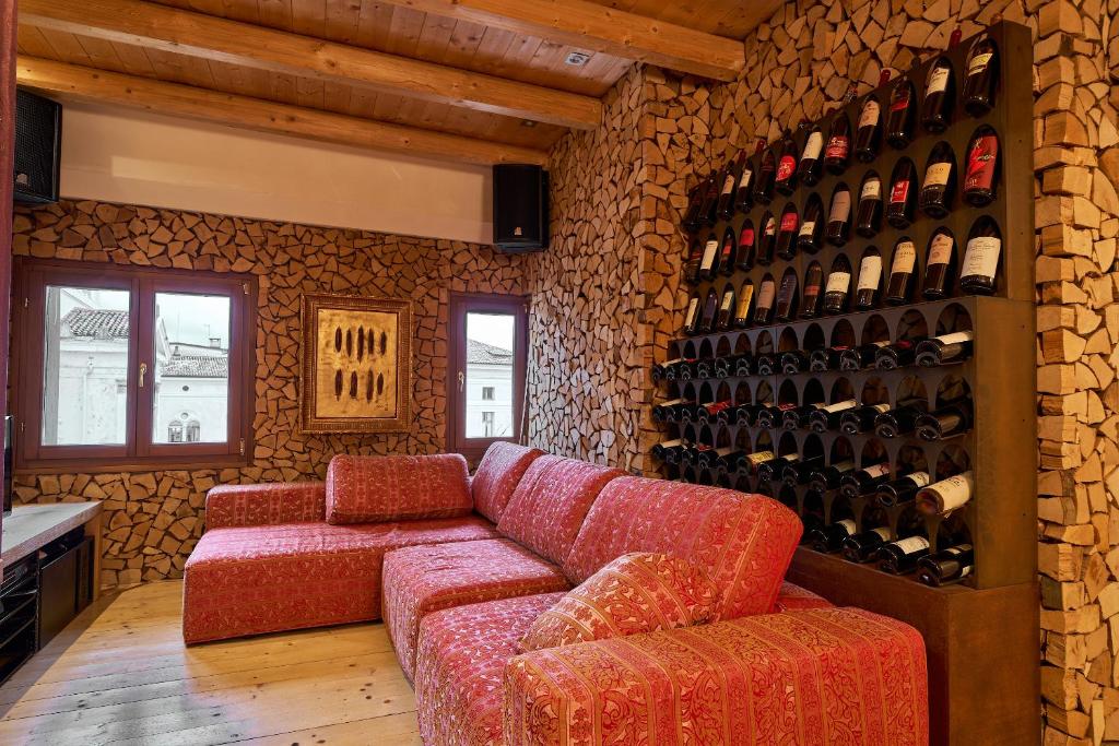 Attico di Piazza Cima في كونيليانو: غرفة بها أريكة وجدار من زجاجات النبيذ