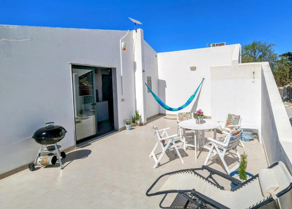Un patio con mesa y sillas y parrilla. en Margus, en Punta Braccetto