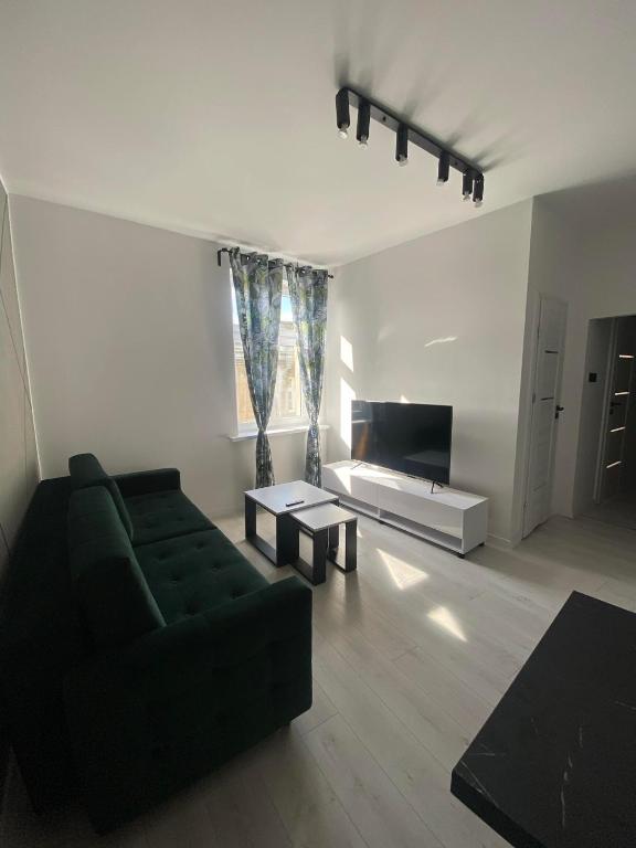 a living room with a green couch and a television at JD Apartment Świętokrzyska in Gniezno