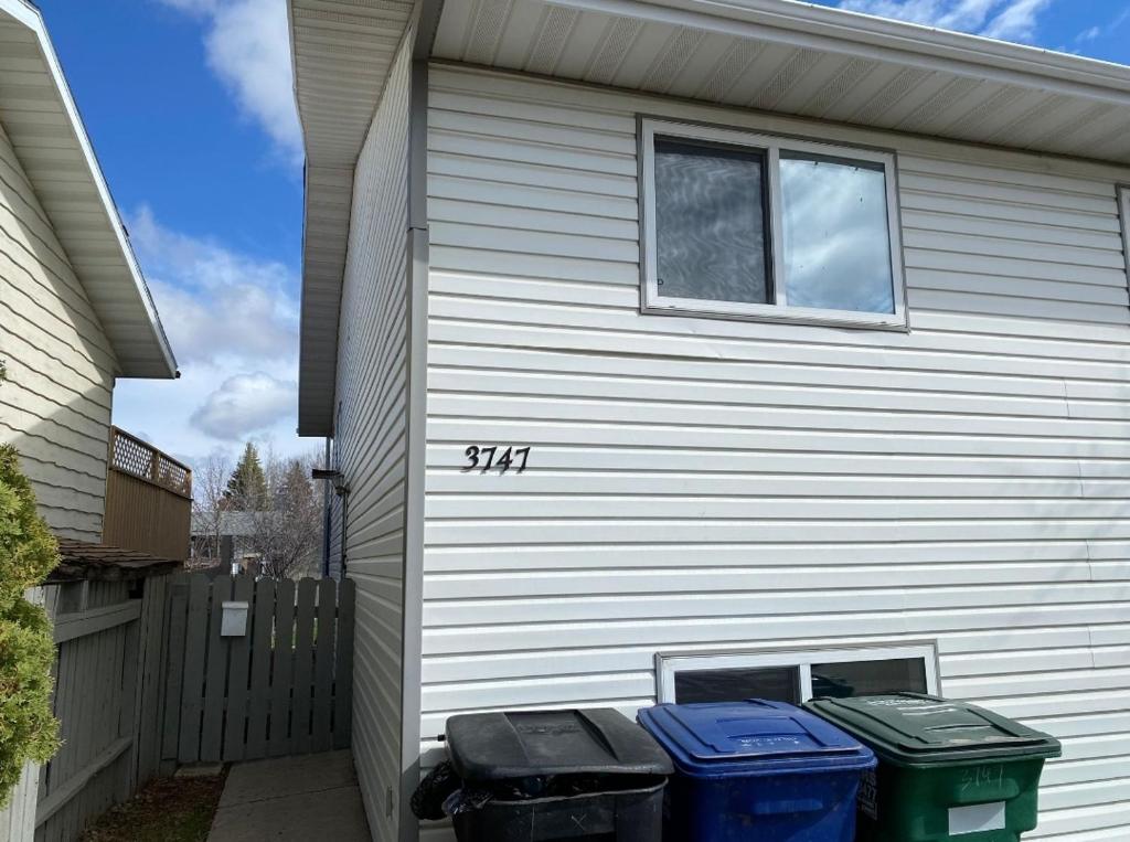 a house with three trash cans in front of it at Bi-Level Suite in Saskatoon in Saskatoon
