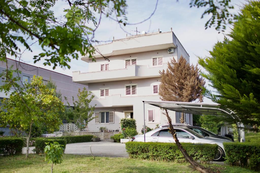 a white building with a car parked in front of it at Rooms by Romi in Durrës