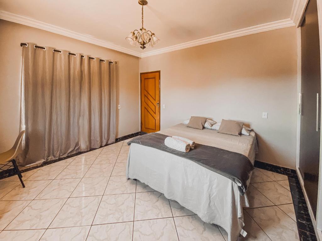 Schlafzimmer mit einem Bett und einem Kronleuchter in der Unterkunft Hostel Network - Faça Novas Conexões, Desfrute de Qualidade e Privacidade in Anápolis