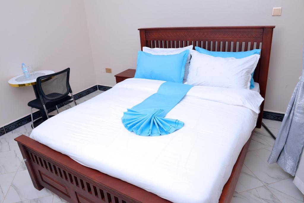 een groot bed met een blauwe paraplu erop bij Kelly Traveller's Inn in Kakinzi