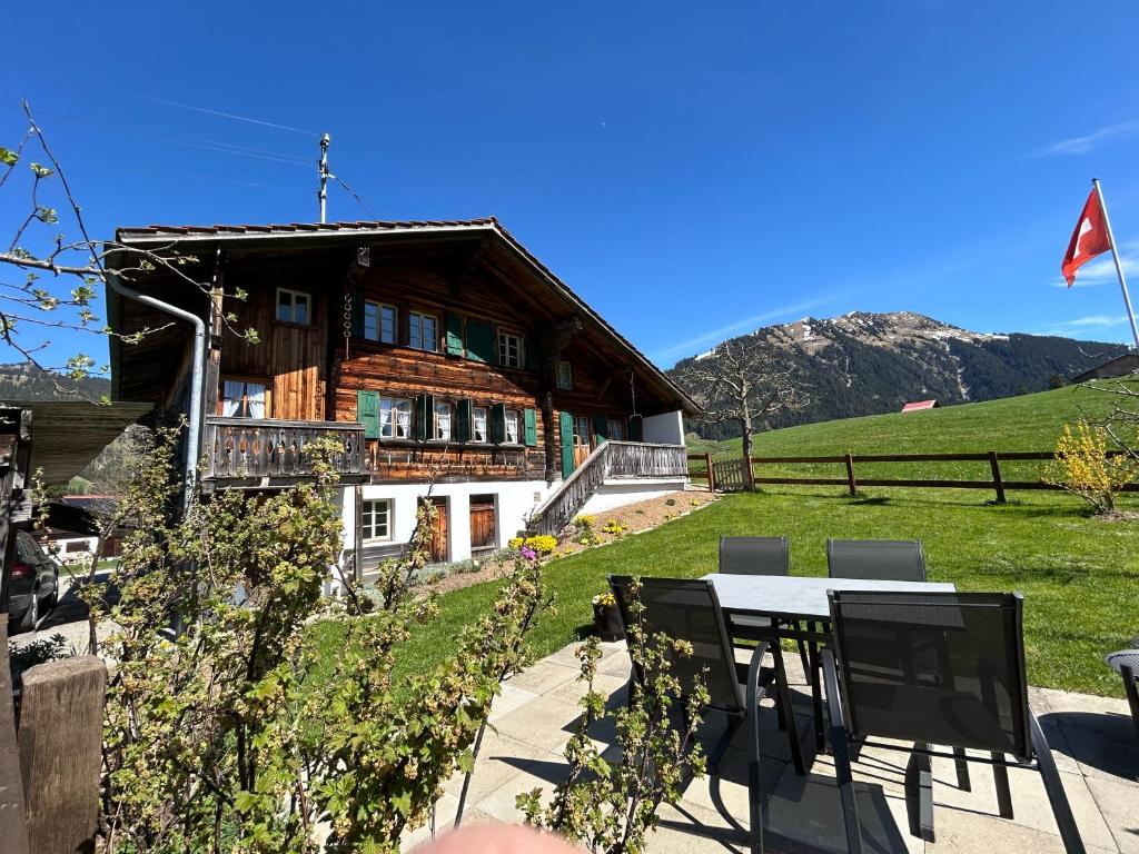 ein Haus mit einem Tisch und Stühlen davor in der Unterkunft Alpenchalet Haldeli Gstaad Ferienwohnung im 1-Stock in Gstaad