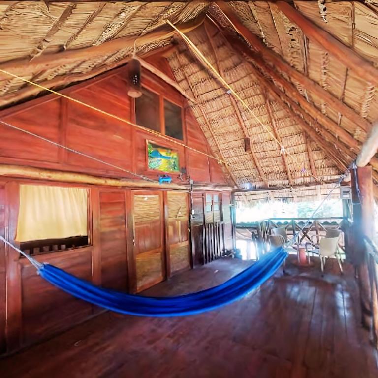 uma rede no meio de um quarto de madeira em Las Chelitas Casa del Mar - Nueva Administración de Maru Mar em Popoyo