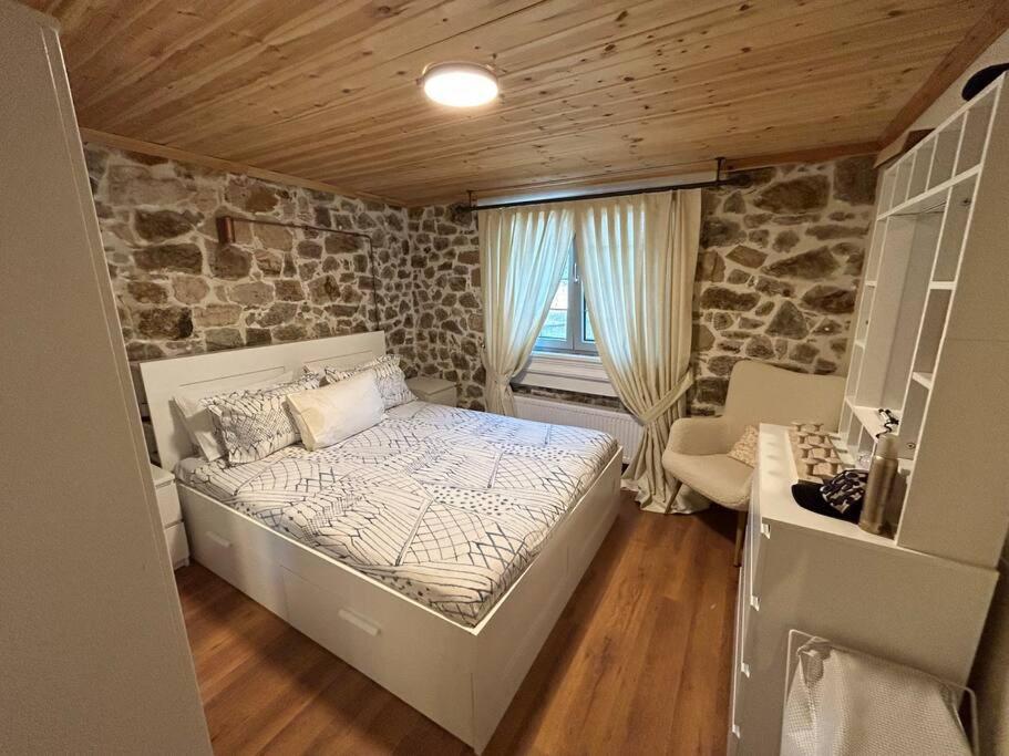 een slaapkamer met een bed en een stenen muur bij Cozy House Nipsa in Nípsa