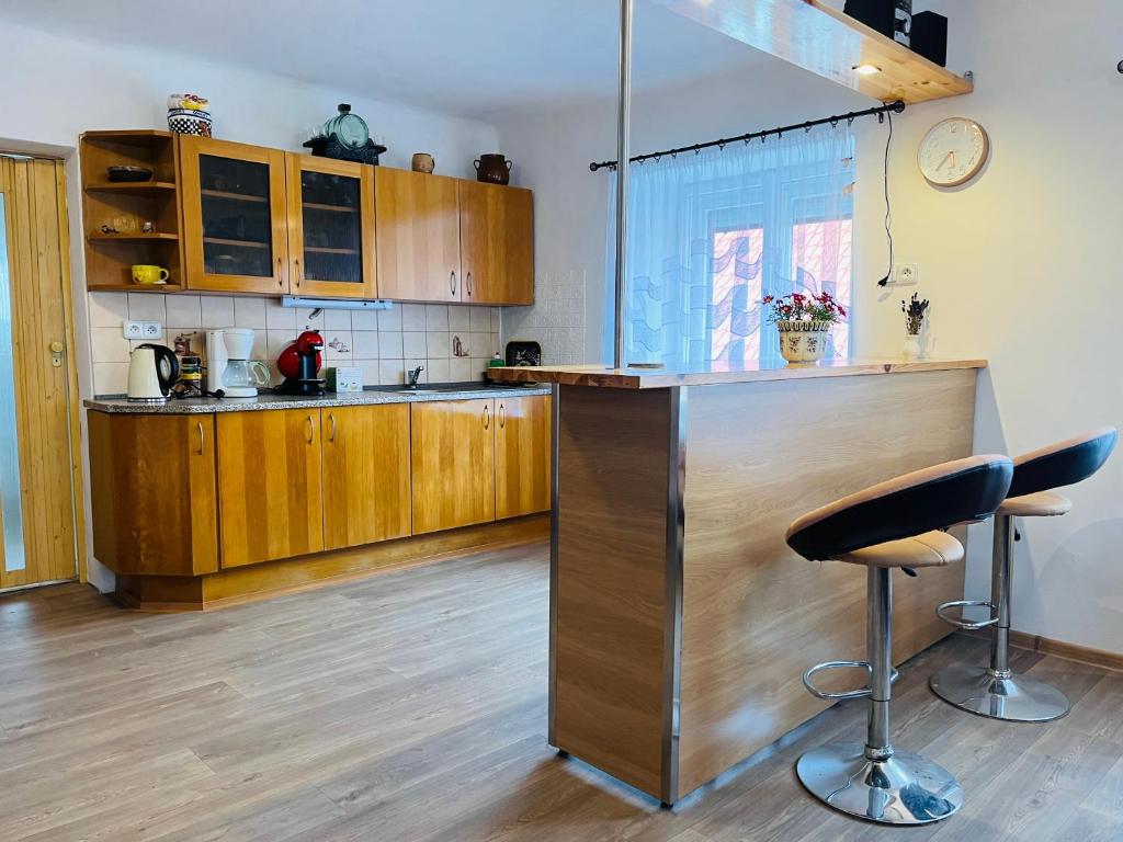 a kitchen with wooden cabinets and a bar with two stools at Chalupa Besednice in Besednice