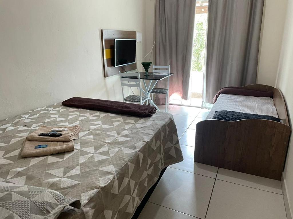 ein Schlafzimmer mit einem Bett, einem TV und einem Stuhl in der Unterkunft Dom Antonio 3 in Campos dos Goytacazes