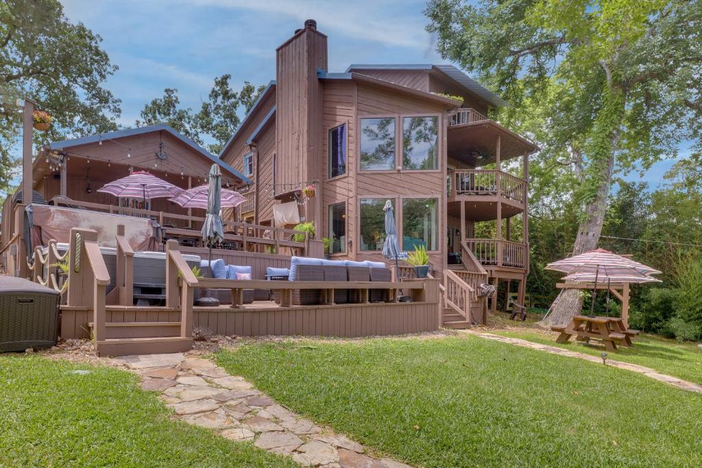 una gran casa de madera con una terraza con sombrillas en Beautiful Lakehouse Hot Tub, Game Room, and Kayaks en Blanchard