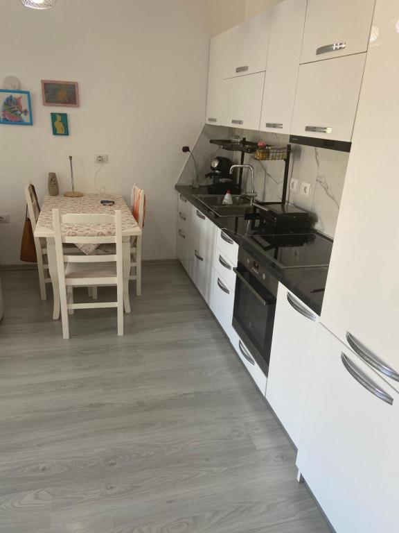 une cuisine avec une table et des placards blancs dans l'établissement one bedroom apartment, à Tirana